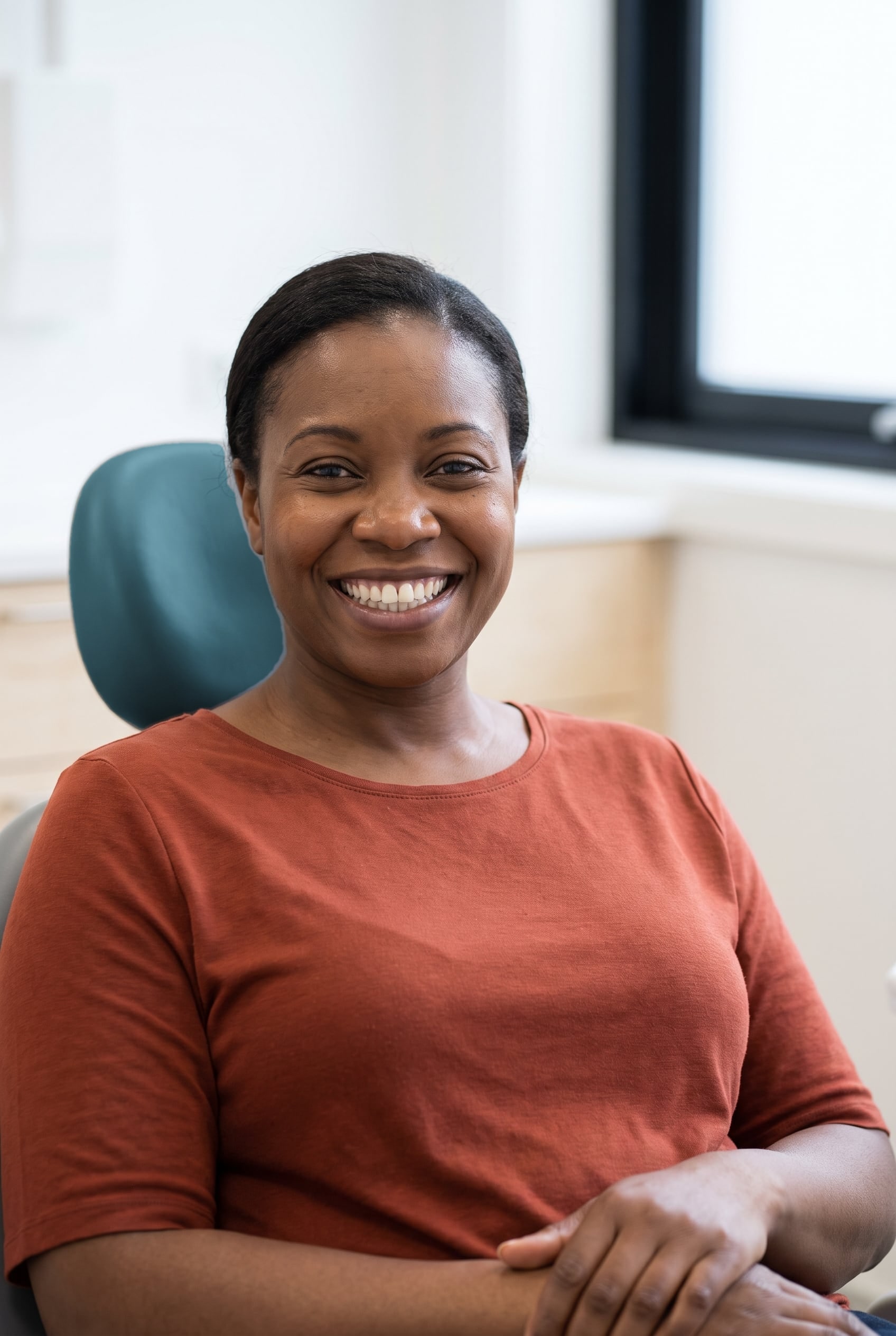 A woman with a bright, natural smile sits relaxed in the dental chair.